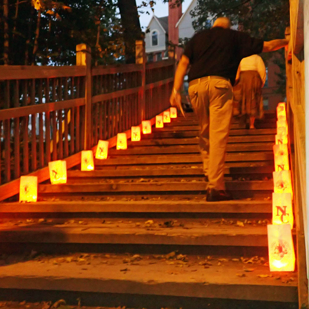 Man walking up stairs on wooden bridge with luminaries